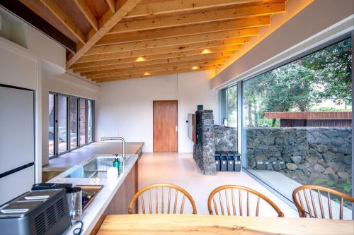 a kitchen with a table and chairs and a stone wall at U.G.SODAM (Uigwisodam) in Seogwipo