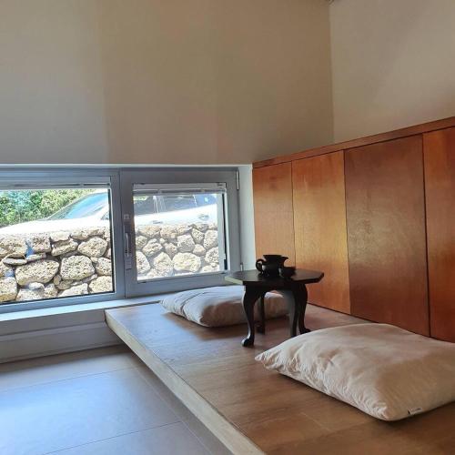 a room with a table and two beds and a window at U.G.SODAM (Uigwisodam) in Seogwipo
