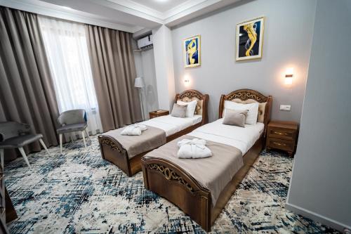 um quarto de hotel com duas camas com toalhas em Hamilton em Tashkent