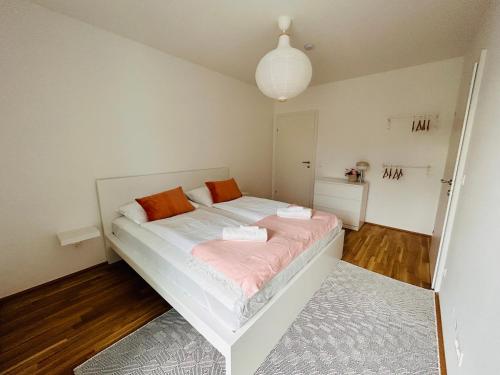 - une chambre avec un lit blanc et des oreillers orange dans l'établissement A Cozy Flat with Flair surrounded by Nature, à Vienne