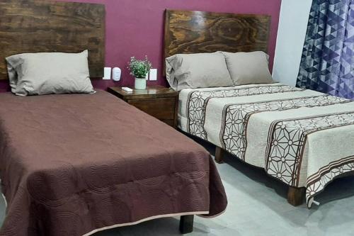 2 camas en una habitación con paredes moradas en Villa De Santos Acapulco Playa Bonfil Alberca, en Acapulco