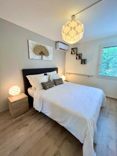 Appartement Idéal في بيتي-بور: غرفة نوم بسرير ابيض كبير ومصباح