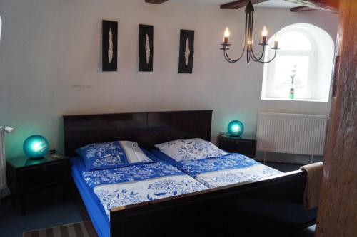 a bedroom with a bed with blue sheets and a chandelier at Mühlenurlaub Südheide in Wittingen