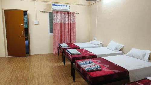 a room with two beds and a door with a window at Nain Guest House in Ujjain