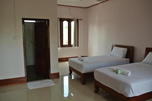 a room with two beds and a mirror at Mama Leurth Sunset Guesthouse in Don Det