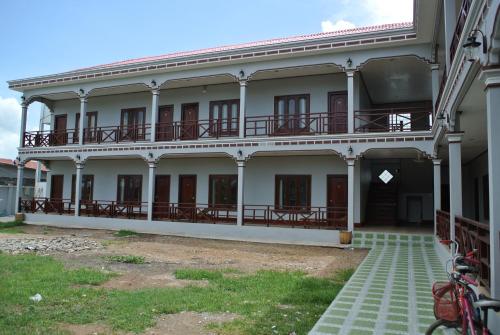 a large white building with a balcony on it at Mama Leurth Sunset Guesthouse in Don Det