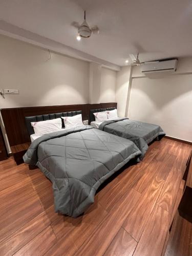 two beds in a room with wooden floors at Hotel Lakshmi Residency in Visakhapatnam