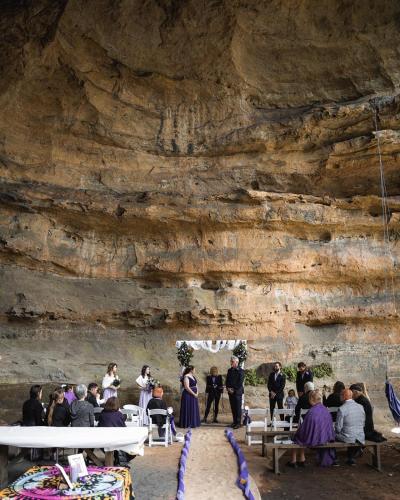 a wedding ceremony in front of a rock wall at Hatter's Hideout Cave and Lodge in Newnes Junction