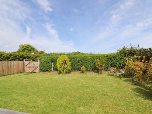 a yard with two benches and a fence at Meols Holiday Lodge in Wirral