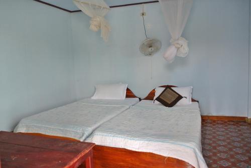 a small bedroom with a bed and a table at Tavendang Guesthouse in Don Det