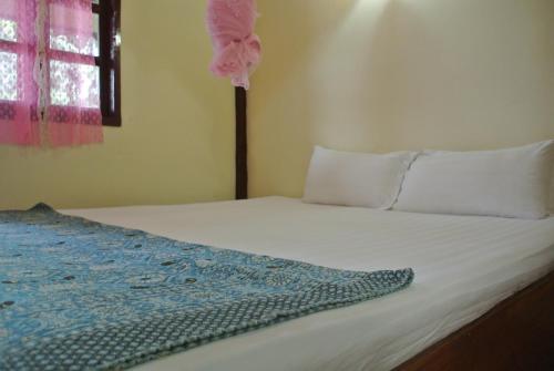 a bed with a pink flower on top of it at Tavendang Guesthouse in Don Det