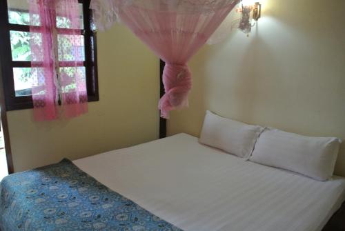 a bedroom with a bed and a window with pink curtains at Tavendang Guesthouse in Don Det
