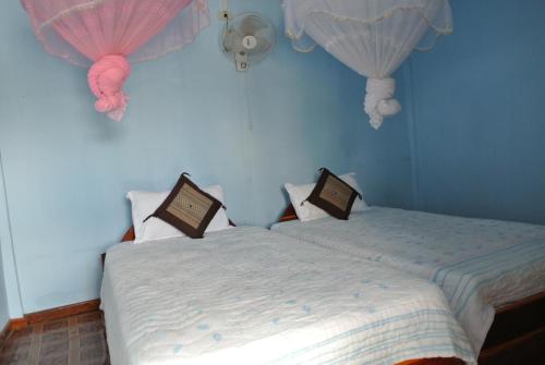 two beds in a room with pink and white curtains at Tavendang Guesthouse in Don Det