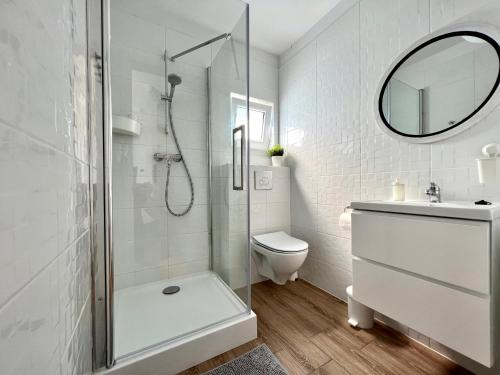 a white bathroom with a shower and a toilet at Domki Maju Maj in Darłowo