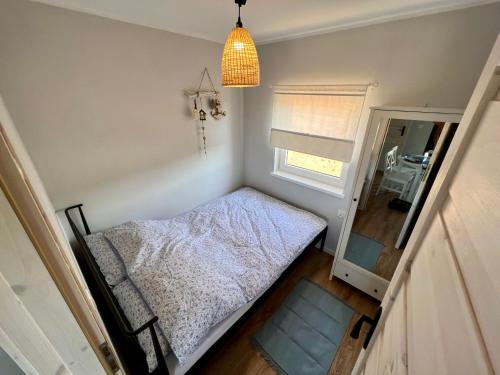 a small bedroom with a bed and a window at Domki Maju Maj in Darłowo