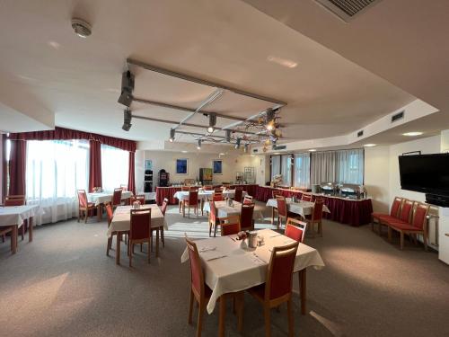 a restaurant with tables and chairs and a flat screen tv at Hotel Estella Superior in Eger