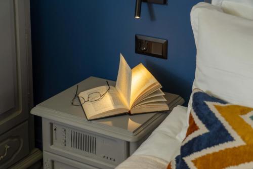 a book and glasses on a table next to a bed at Maria Luisa by INTROVERT HOTELS in Sofia