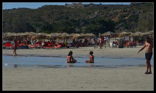 two people sitting in the water on a beach at Mouri Village in Aïkiryiánnis