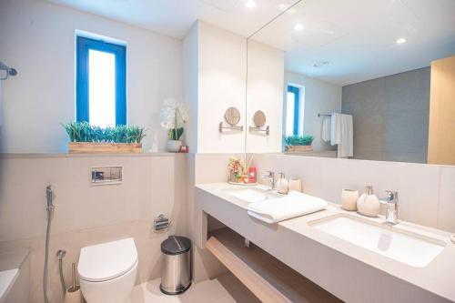 a bathroom with two sinks and a toilet and a mirror at Luxury 3 bdr Villa by the sea 54 in Fujairah