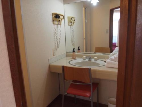 a bathroom with a sink and a chair in front of a mirror at Senkei Plaza in Hakone