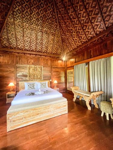 a bedroom with a large bed and a wooden ceiling at The Banana’s Kumbe Villa in Tampaksiring