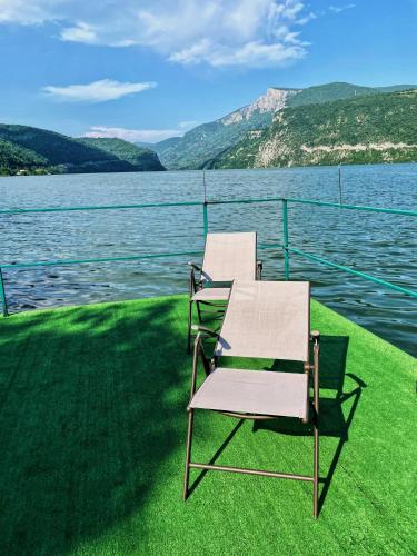 two chairs sitting on the grass next to a body of water at Casa Anastasia in Dubova