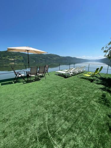 un grupo de sillas y una sombrilla junto a un lago en Casa Anastasia, en Dubova