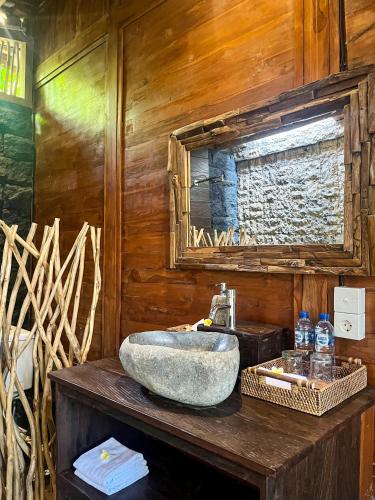 a bathroom with a sink on a wooden wall at The Banana’s Kumbe Villa in Tampaksiring