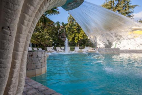 a pool with a water fountain in a yard at Hotel Terme Patria in Abano Terme
