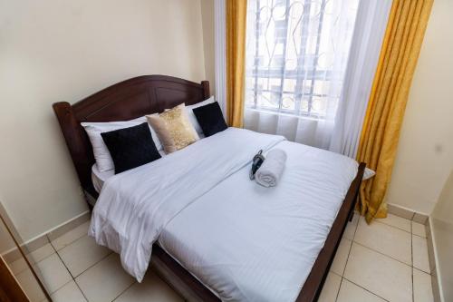 a bedroom with a bed with white sheets and a window at Greatwall in Athi River