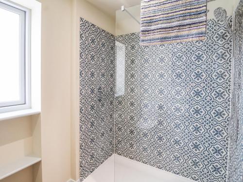 a bathroom with a shower with blue and white tiles at Church Farm Barn in Saxmundham
