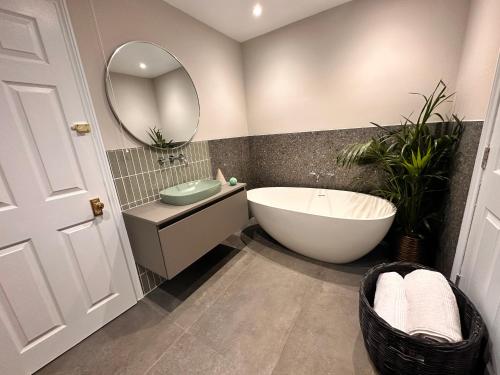 a bathroom with a tub and a sink and a mirror at Cotswolds Retreat - Bath & Castle Combe - Hot Tub in Chippenham