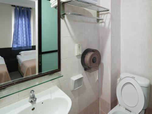 a bathroom with a toilet and a sink and a mirror at Amrise Hotel in Singapore