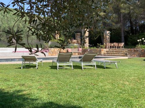 drie stoelen en een tafel in het gras bij Bastide Sainte Trinide in Sanary-sur-Mer