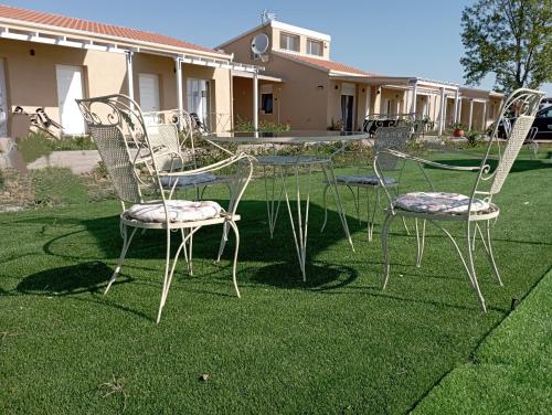 three chairs and a table on a lawn at sylias village in Skála Korinoú