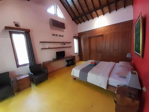ein Schlafzimmer mit einem Bett und einem Stuhl in einem Zimmer in der Unterkunft Pondok IJo Villa in Timuran