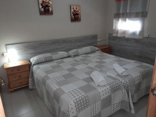 a bedroom with a large bed with a checkered blanket at Camping las Catalinas in Ríolobos