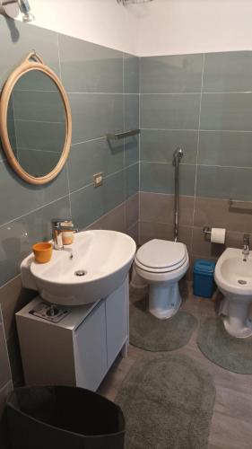 een badkamer met een wastafel, een toilet en een spiegel bij dg.apartaments in Alcamo