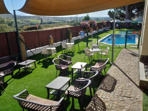 un patio con mesas y sillas y una piscina en Camping las Catalinas, en Riolobos