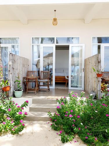 a patio with a table and chairs and flowers at Lucky Spot Beach Bungalow in Song Cau