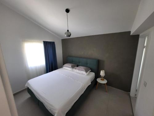 Un dormitorio con una gran cama blanca y una ventana en Apartmani J&I, en Pakoštane
