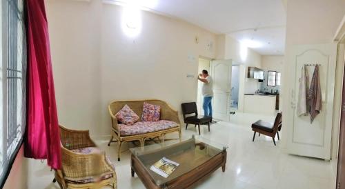 a man is standing in a living room at Raintree Garden in Mysore