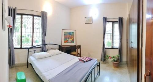 sypialnia z łóżkiem i 2 oknami w obiekcie Raintree Garden w mieście Mysuru