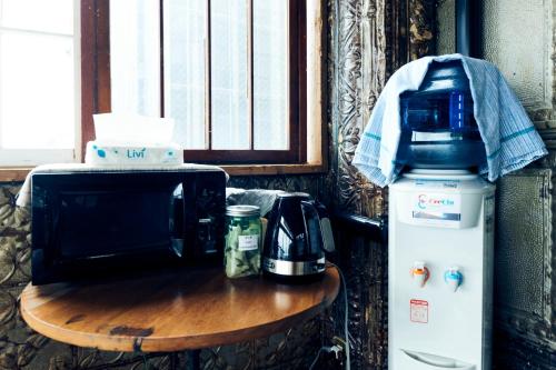 a microwave and a coffee maker on a table next to a table with a coffee at Guest House CARAPAN in Kagoshima