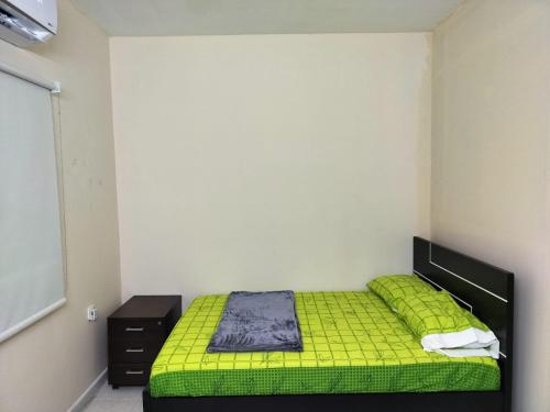 Prem Home Stay في الشارقة: غرفة نوم مع سرير أخضر وخزانة سوداء