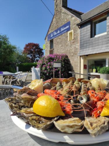 a plate of seafood on a table with a lemon at Logis Hôtel Vannes Nord Le Clos Des Hortensias in Locqueltas