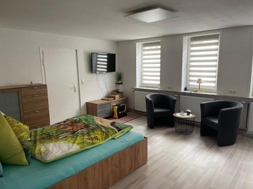 1 dormitorio con 1 cama y sala de estar con sillas en Ferienwohnung Adrian, en Sankt Andreasberg