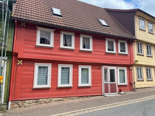 a red house with white windows on a street at Ferienwohnung Adrian in Sankt Andreasberg