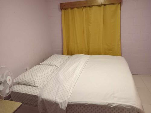 a bed in a room with a yellow curtain at JeZAmi Hideaway in Nuku‘alofa