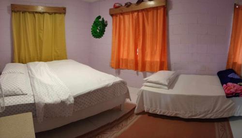 a bedroom with two beds and a window with curtains at JeZAmi Hideaway in Nuku‘alofa